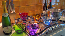 3d обои Бутылка шампанского La Montina и цветные салатницы на кухонной плите  интерьер