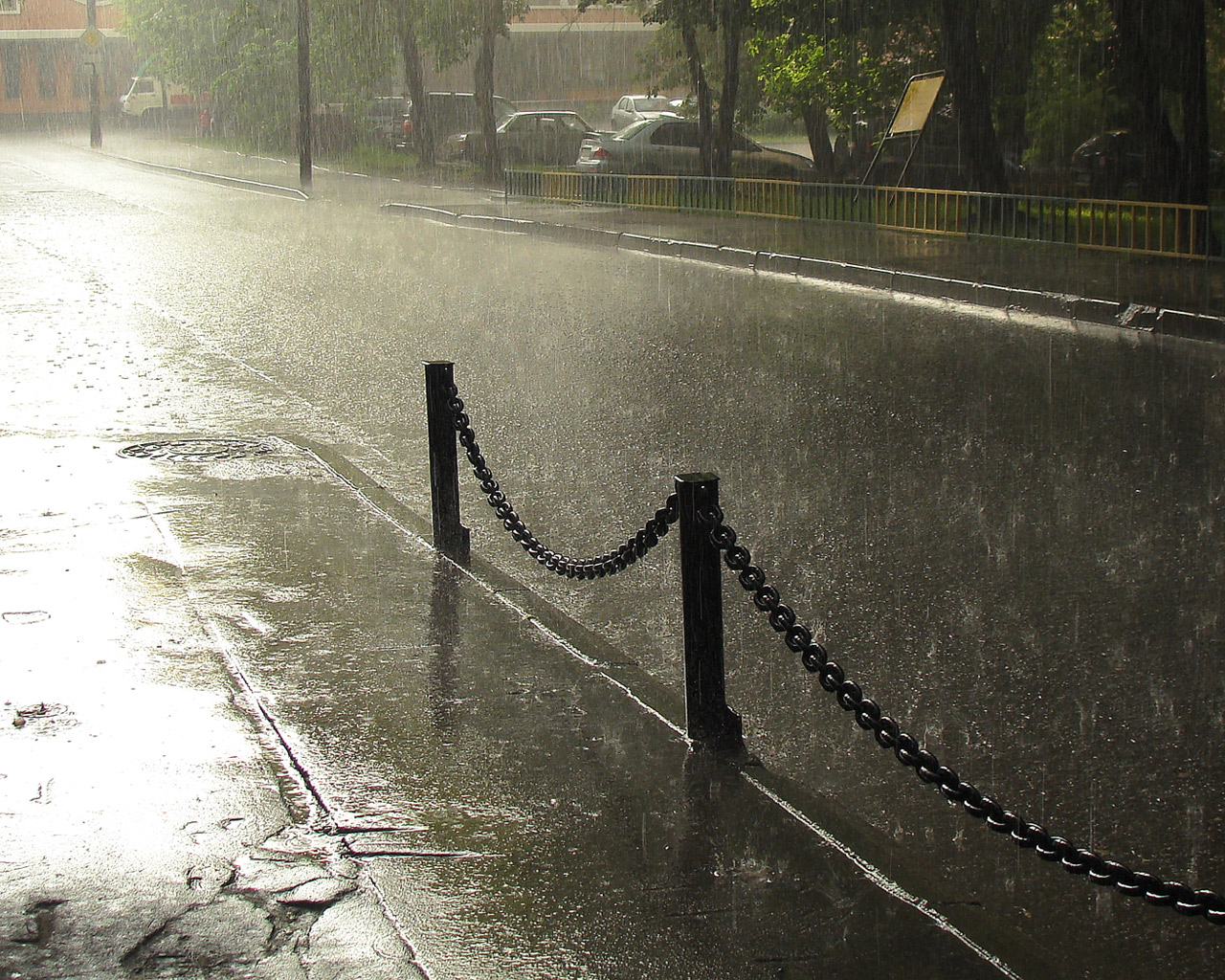 3d обои Дождь в городе, капли лупят по асфальту мостовой, поливают дворы и деревья. Намокла и массивная железная цепь, отделяющая тротуар от дороги.  авто # 18852